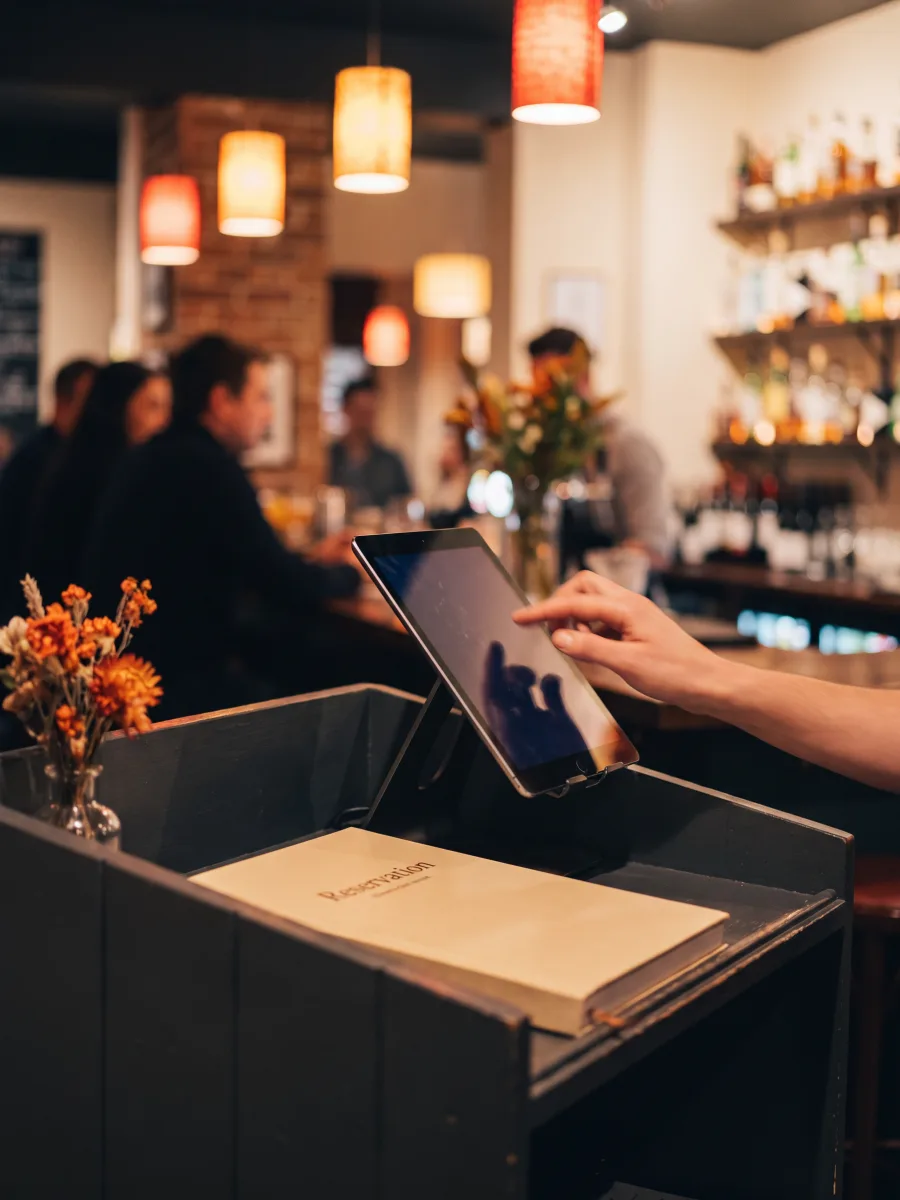 A hand entering an email into a restaurant check in tablet at the counter